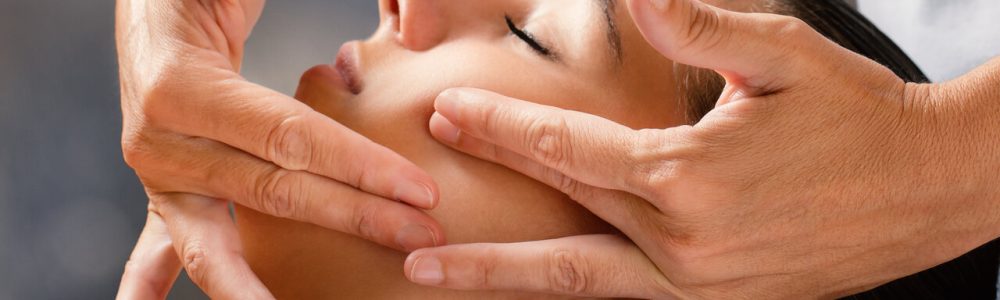 Close up portrait of woman having facial cosmetic therapy. Therapist applying cream on female cheek.